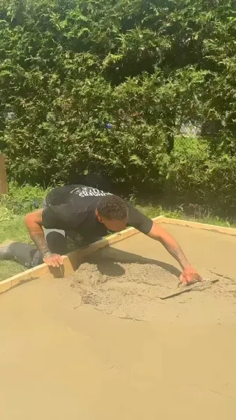 Tradesperson hand-troweling the concrete surface for a smooth finish